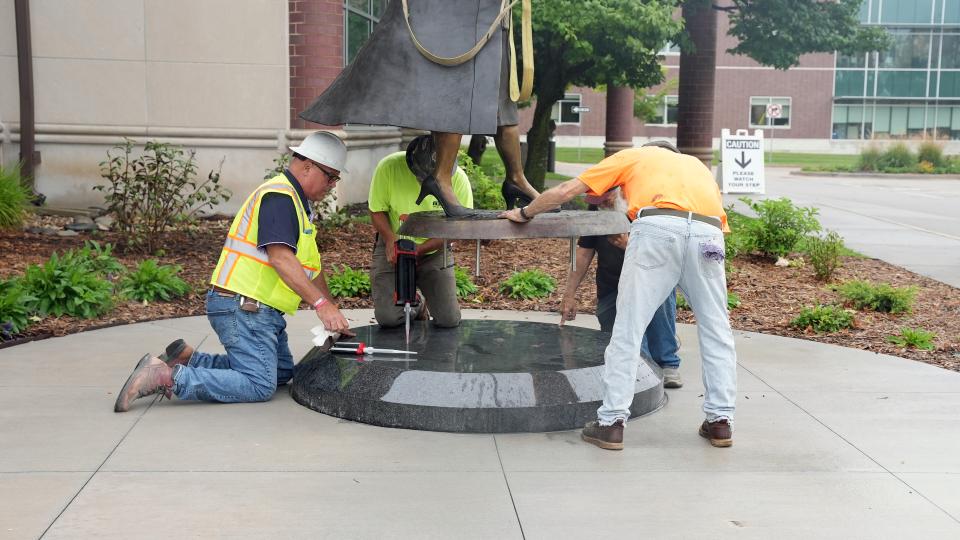 A construction crew lowers the Dr. Johnson statue onto a base.