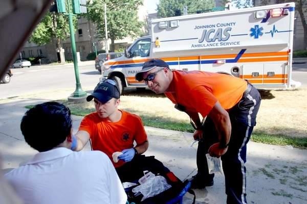 Ambulance employees helping someone on the sidewalk