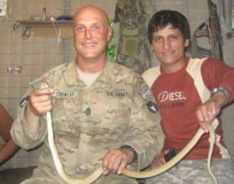 photo of Dave Crowley in uniform holding a snake