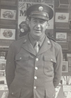 Franklin Burkart standing in front of a stand in his Army uniform