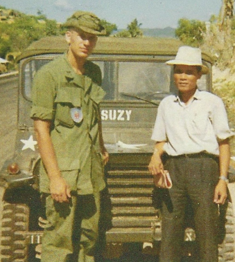 Ray Helmer standing next to a Vietnamese farmer in front of a military jeep