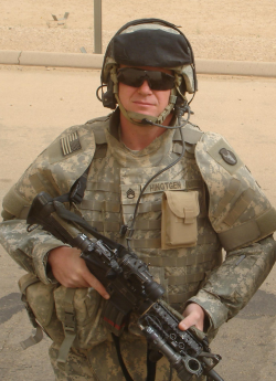 Larry Hiingtgen standing in Iraq in full Army gear holding a rifle