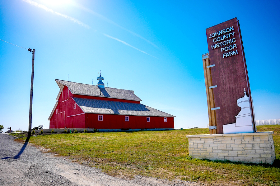 Johnson County Historic Poor Farm sign with red barn in background