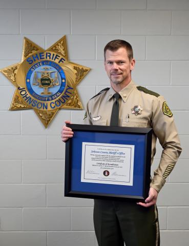 Major Randy Lamm of the Johnson County Sheriff's Office stands with the certificate of accreditation from the Iowa Law Enforcement Accreditation Program. 